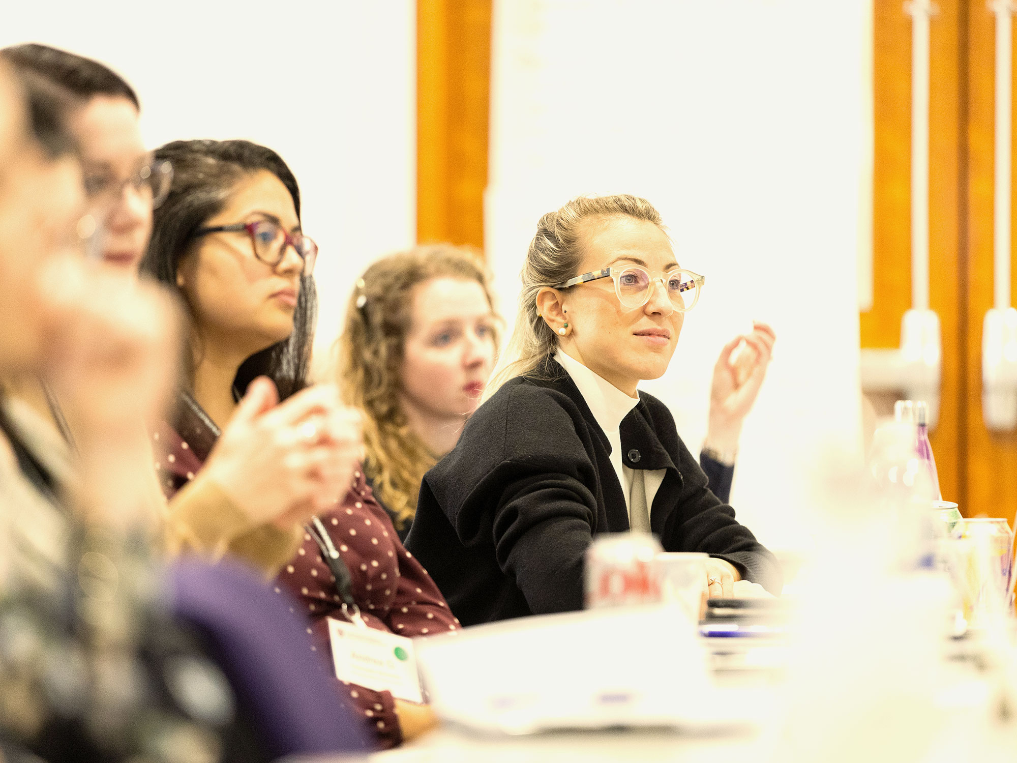 Woman in glasses listening thoughtfully during a leadership seminar.