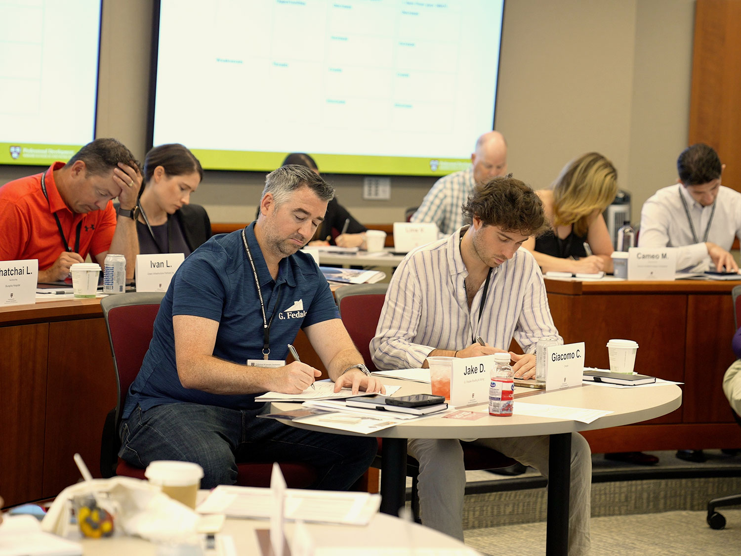 Professional development program participants write at their desks in a classroom.